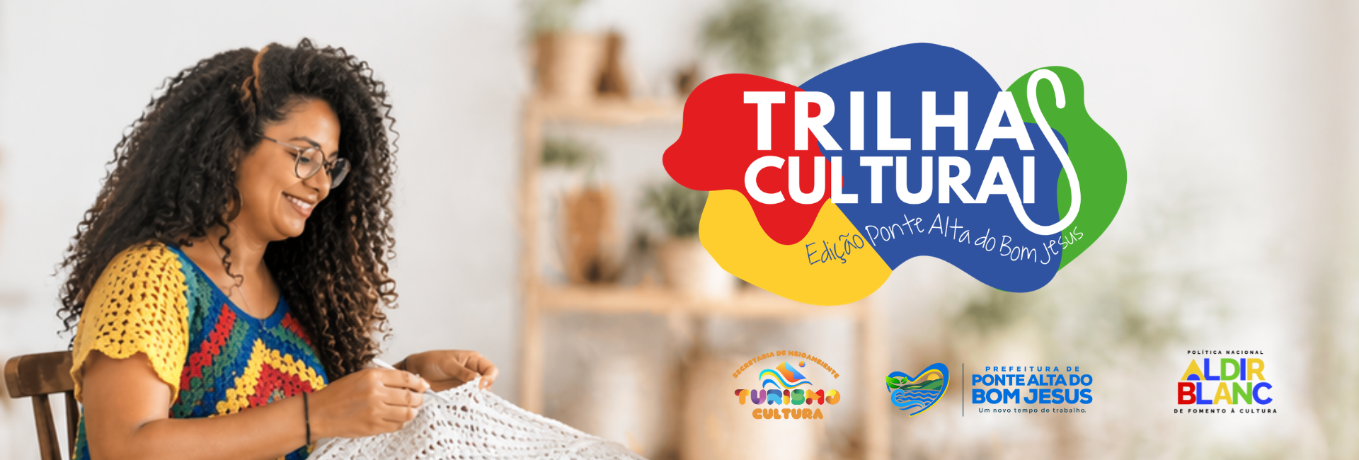 Card digital do Edital Trilhas Culturais – Edição Ponte Alta do Bom Jesus. À esquerda, mulher sentada produz uma peça branca em crochê. À direita, aparece a logomarca do Trilhas Culturais. Na parte inferior, estão as marcas da Secretaria de Meio Ambiente, Turismo e Cultura, da Prefeitura de Ponte Alta do Bom Jesus e da Política Nacional Aldir Blanc. Clique na imagem para acessar a página com mais informações sobre o edital.